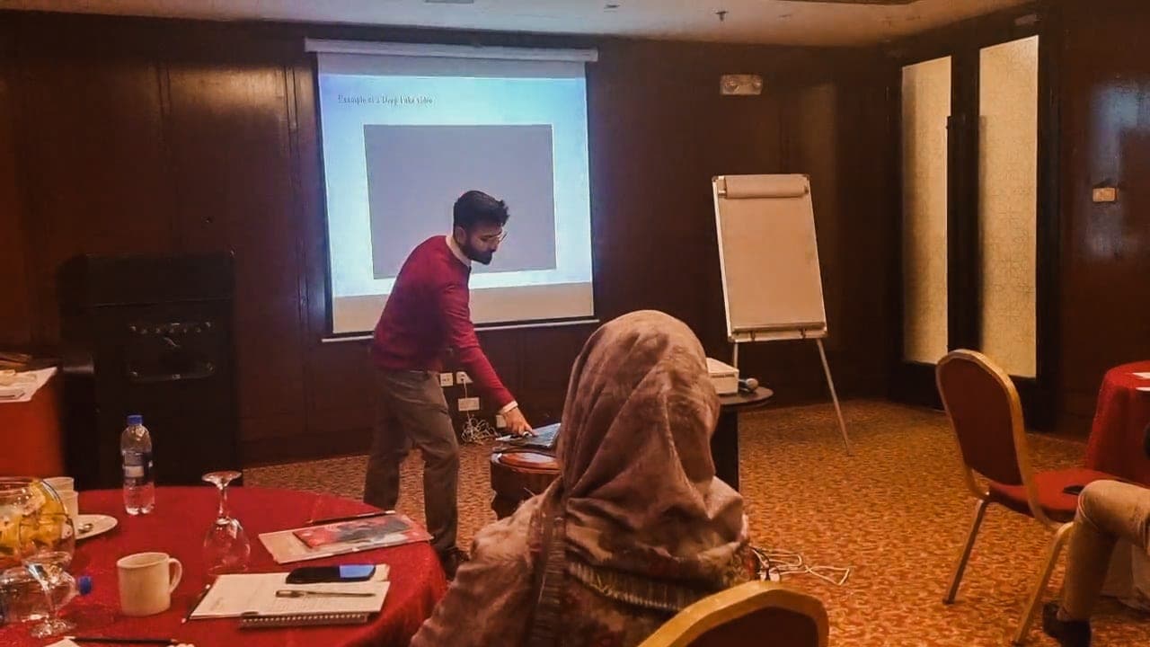 Abdullah leading a workshop, presenting an example of a deepfake video